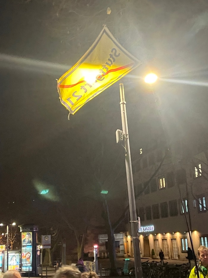Ein Banner mit dem Logo der Stuttgart-21-Gegner (durchgestrichener Schriftzug Stuttgart-21) hängt von einem Laternenmast in der Nähe des Schlossplatzes Stuttgart